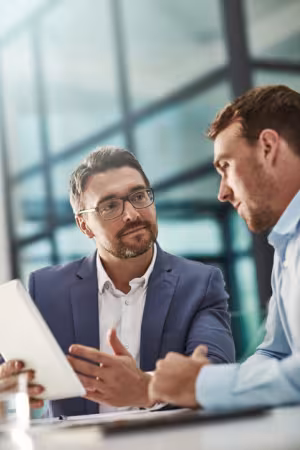 Photo of two mean discussing at a table